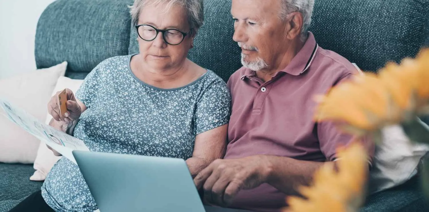 Older couple reading through their coverage papers on the sofa