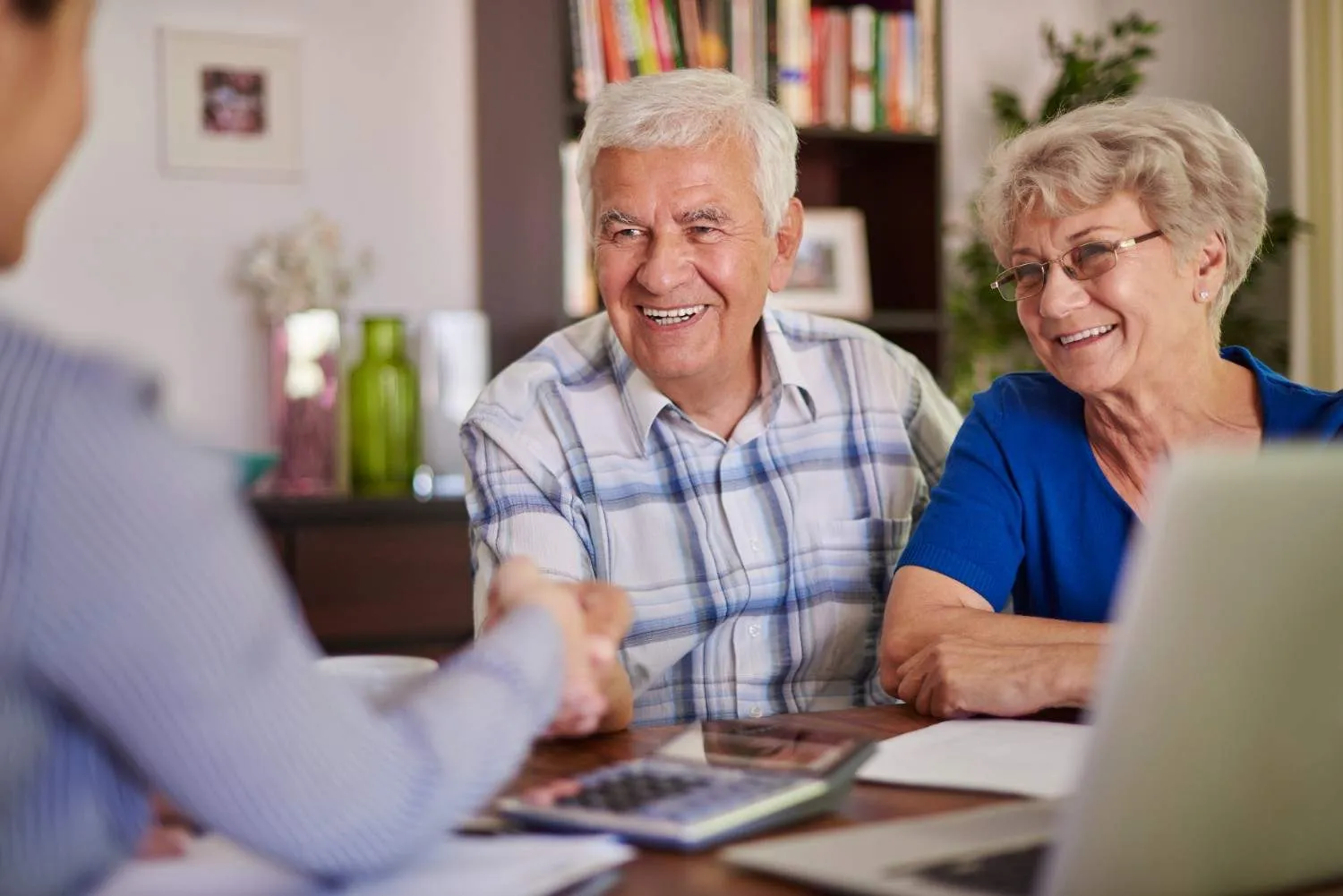 Older couple shaking hands over their finished coverage papers