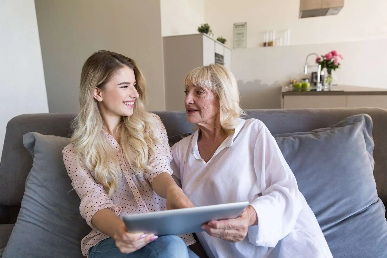 Older mother and adult daughter reading a tablet together